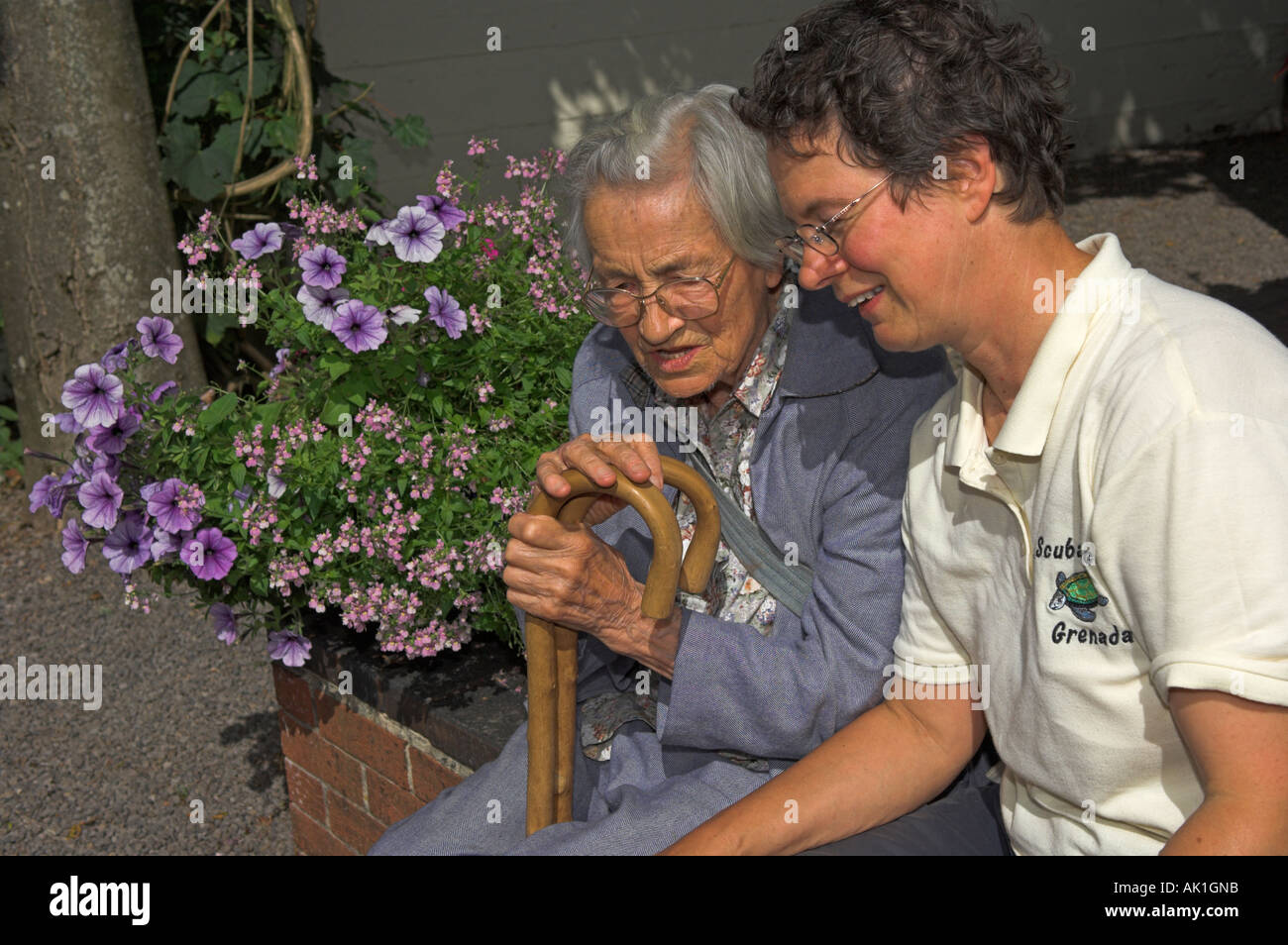 Alte Mutter und Erwachsene Tochter sprechen im Garten Stockfoto