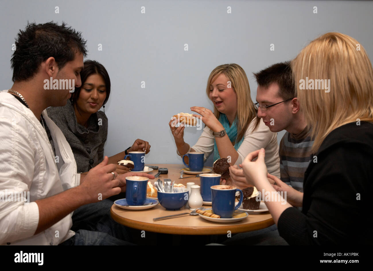 Gruppe von fünf Mischlinge Studenten sitzen in einem Café bei einer Tasse Kaffee und einige Brötchen Stockfoto