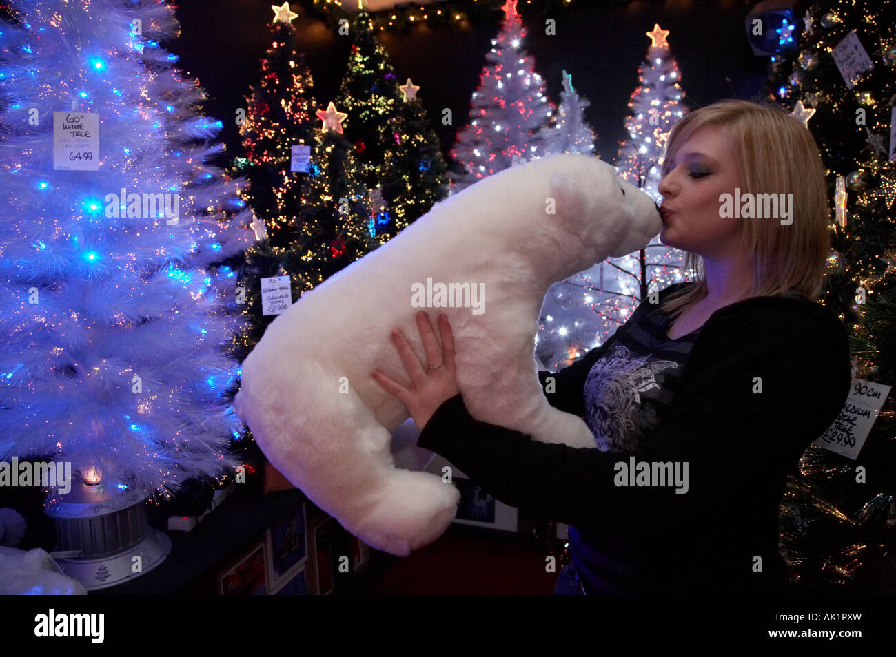 blonde kurzhaarige irische Studentin küssen ein Stofftier Eisbär im Shop Verkauf Weihnachtsbäume und Dekorationen Stockfoto