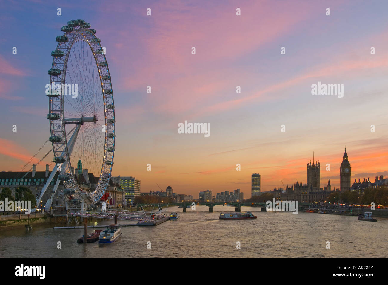 Blick auf das London Eye, Westminster Bridge und den Houses of Parliament von Charing Cross Fußgängerbrücke am Sonnenuntergang Dämmerung am Abend. Stockfoto