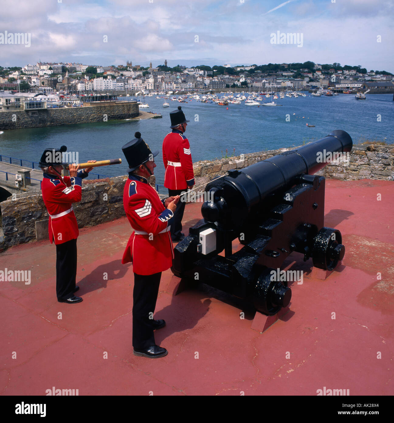 Drei Soldaten in roten militärischen Uniform Feuer der Mittag Tag Artillerie Salutschüsse am Castel Cornet St Peter Port Guernsey Stockfoto