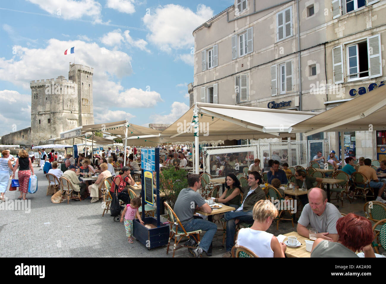 Straßencafé in Vieux-Port mit der Tour Saint-Nicolas hinter La Rochelle, Poitou-Charentes, Frankreich Stockfoto