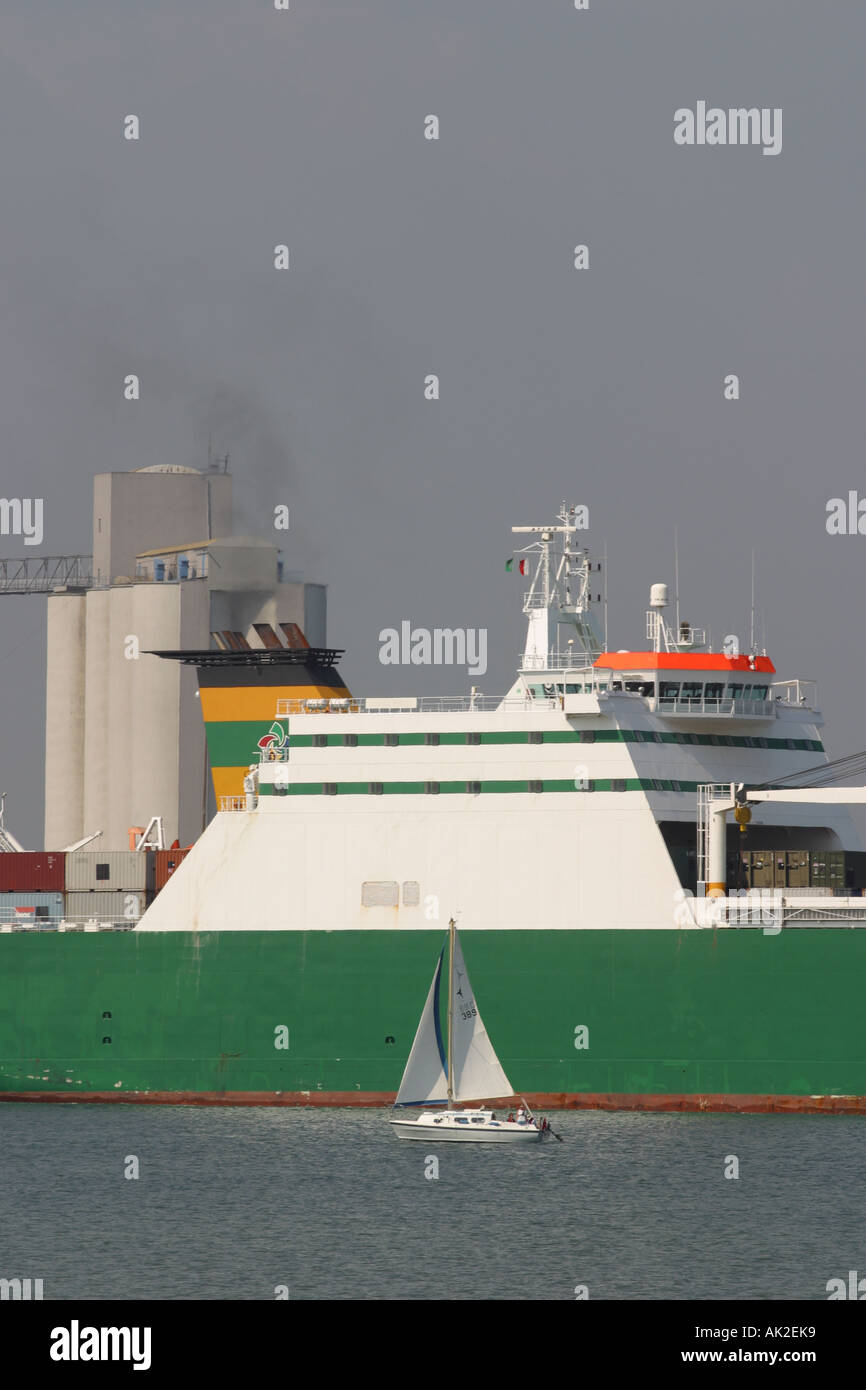 Kommerzielle Schifffahrt große Containerschiff Blätter Southampton Docks mit kleinen privaten Yacht neben Stockfoto