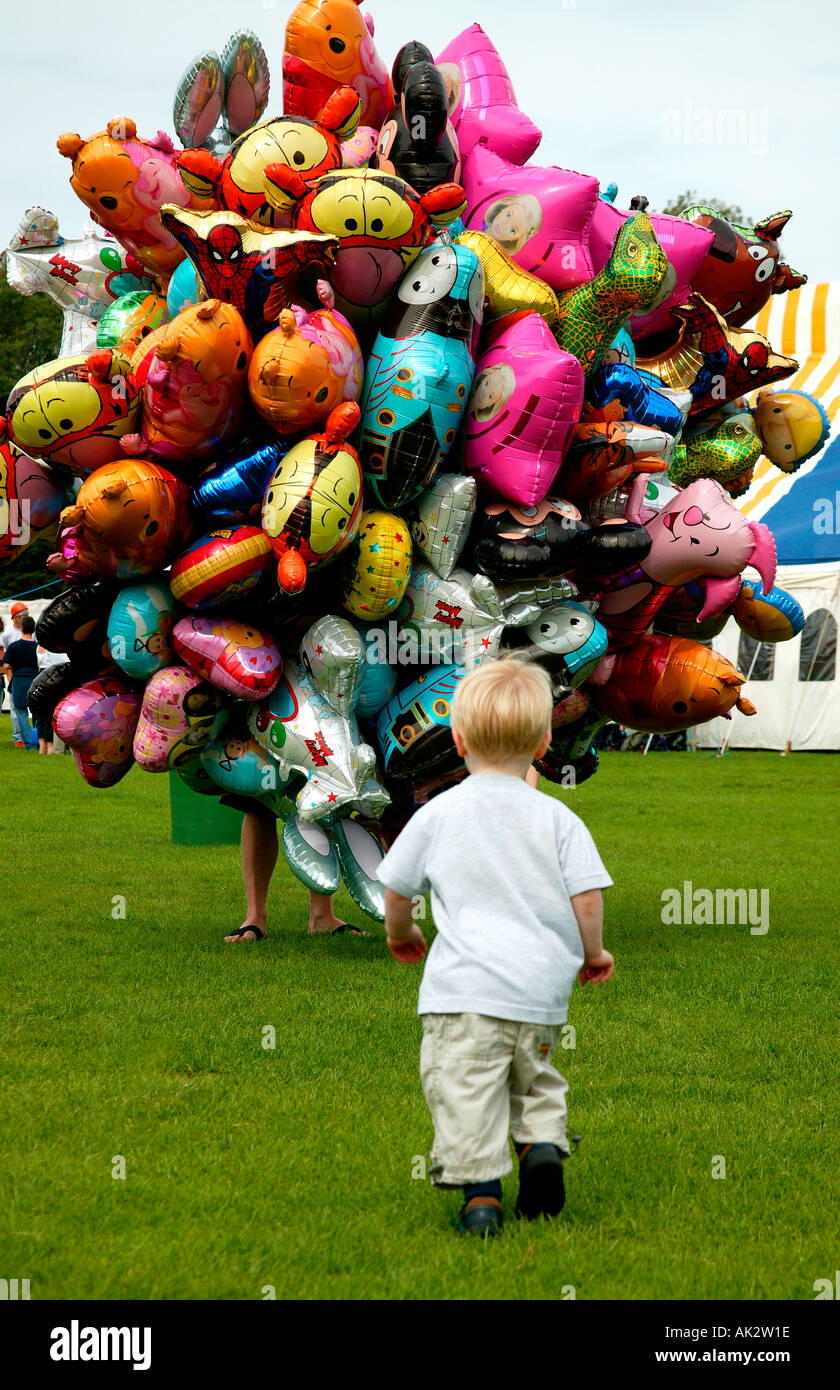 Kleiner Junge im Park läuft auf jemand verkauft Luftballons Stockfoto