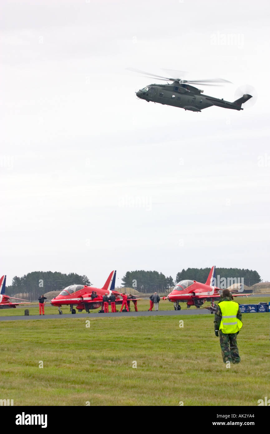 28 Squadron RAF Merlin HC3 Hubschrauber schwebt über Red Arrows Hawk Flugzeuge mit Besatzung auf Stockfoto