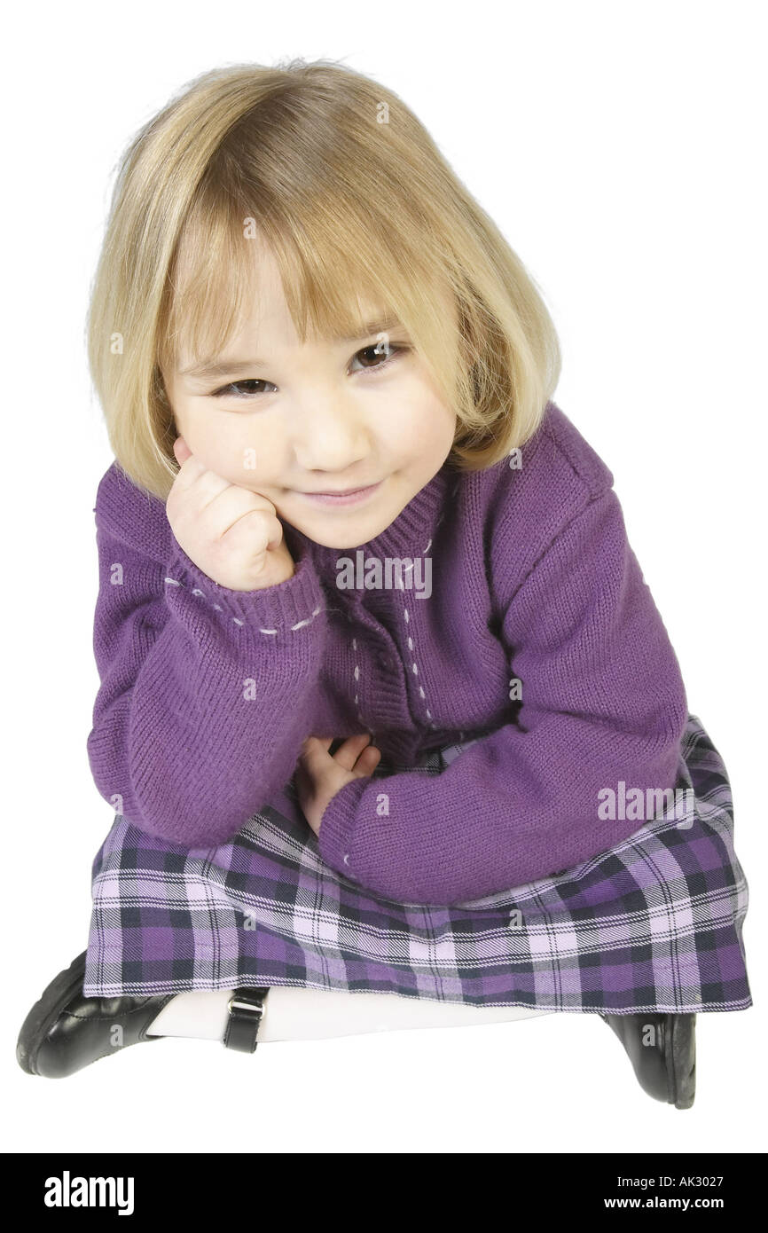 Junge blonde Mädchen Schneidersitz auf dem Boden sitzend und runzelt die Stirn Stockfoto