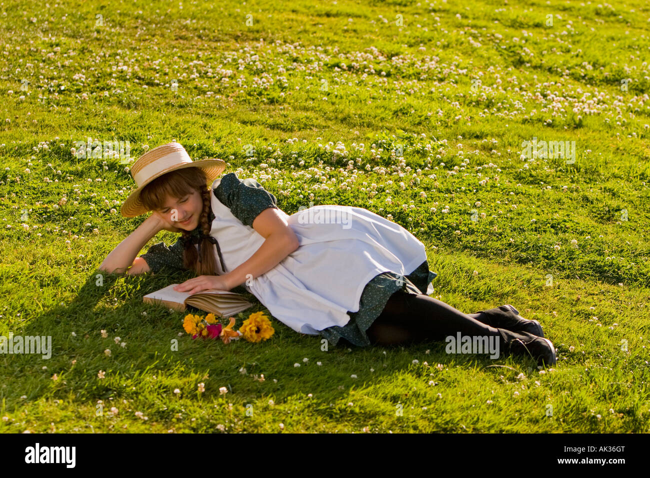 Junges Mädchen mit Hut und Zöpfe Anne of Green Gables Lesen eines Buches in einem Feld in der Nähe von Green Gables nach Hause Cavendish PEI Kanada Stockfoto