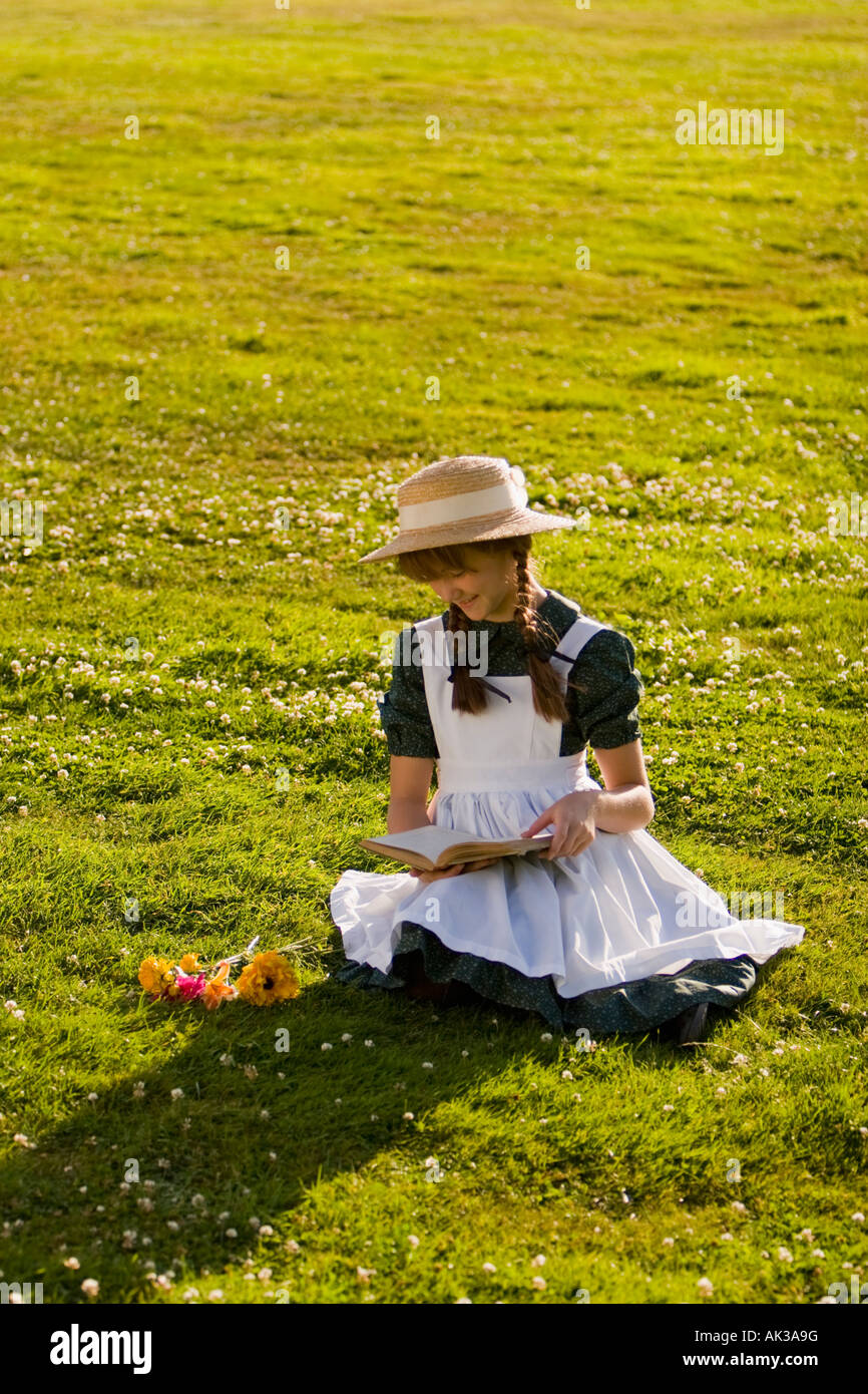Junges Mädchen mit Hut und Zöpfe Anne of Green Gables Lesen eines Buches in einem Feld in der Nähe von Green Gables nach Hause Cavendish PEI Kanada Stockfoto