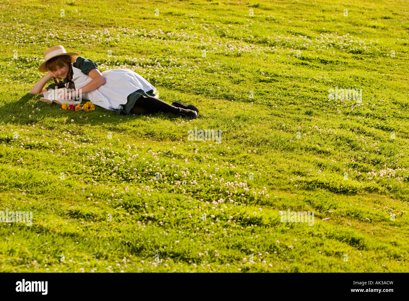 Junges Mädchen mit Hut und Zöpfe Anne of Green Gables Lesen eines Buches in einem Feld in der Nähe von Green Gables nach Hause Cavendish PEI Kanada Stockfoto