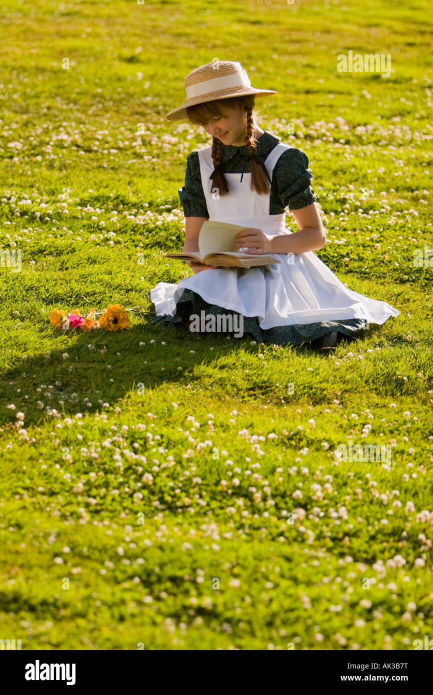 Junges Mädchen mit Hut und Zöpfe Anne of Green Gables Lesen eines Buches in einem Feld in der Nähe von Green Gables nach Hause Cavendish PEI Kanada Stockfoto