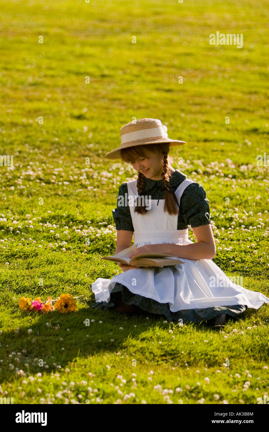 Junges Mädchen mit Hut und Zöpfe Anne of Green Gables Lesen eines Buches in einem Feld in der Nähe von Green Gables nach Hause Cavendish PEI Kanada Stockfoto