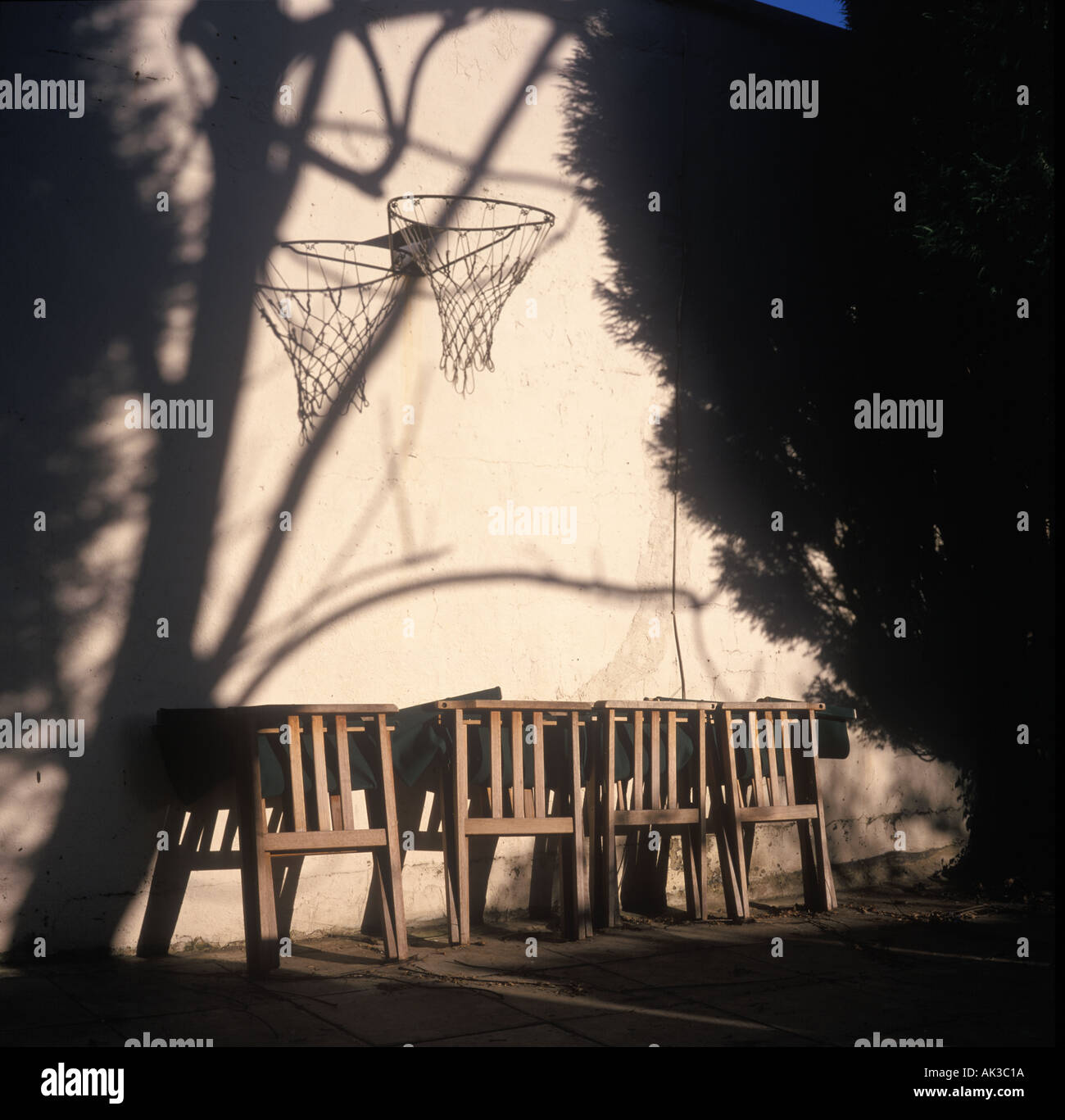 Gartenstühle geschlossen für den Winter gegen eine Wand mit Basketballkorb über UK. Stockfoto
