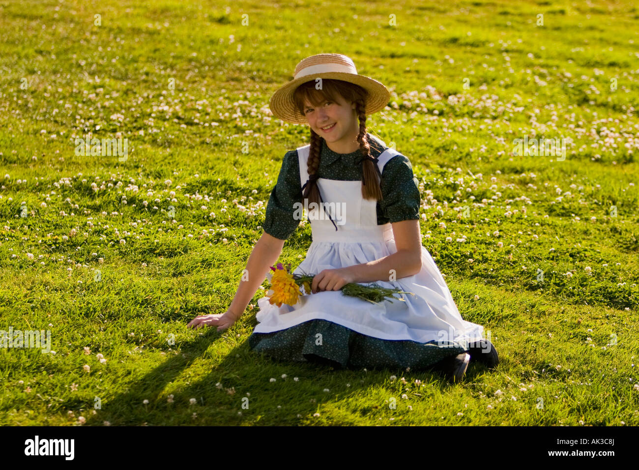 Junges Mädchen mit Hut und Zöpfe Anne of Green Gables mit Blumen in einem Feld in der Nähe von Green Gables nach Hause Cavendish PEI Kanada Stockfoto