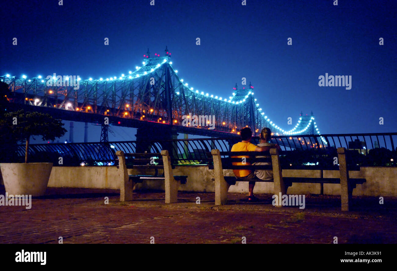 Ein junges Paar sitzt auf einer Parkbank aus Sutton Place in New York City USA mit Blick auf die 59th Street Bridge Stockfoto