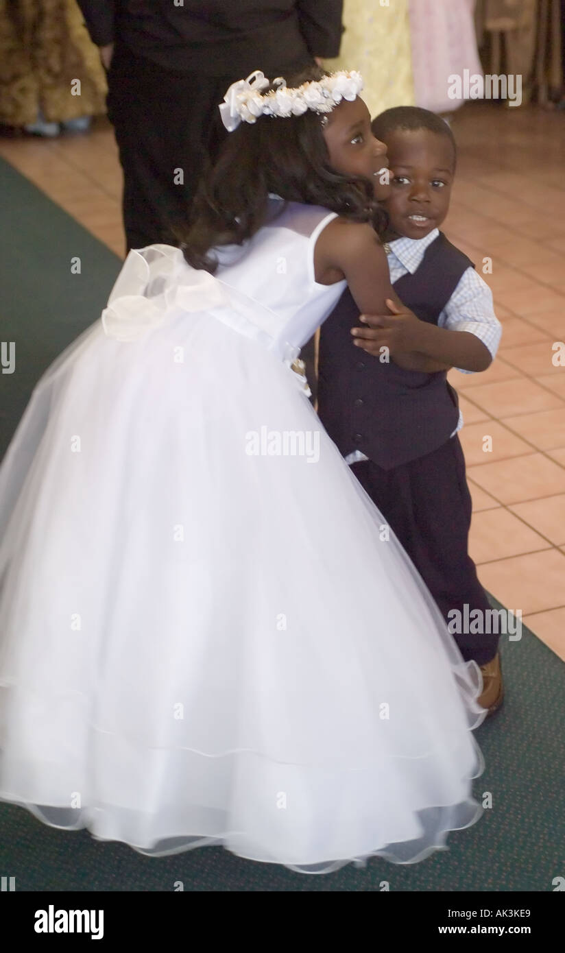 Eine afroamerikanische Blume umarmt ihr Ring Bearer Bruder nach der Teilnahme an einem interracial Hochzeit in Santa Ana, Kalifornien Stockfoto