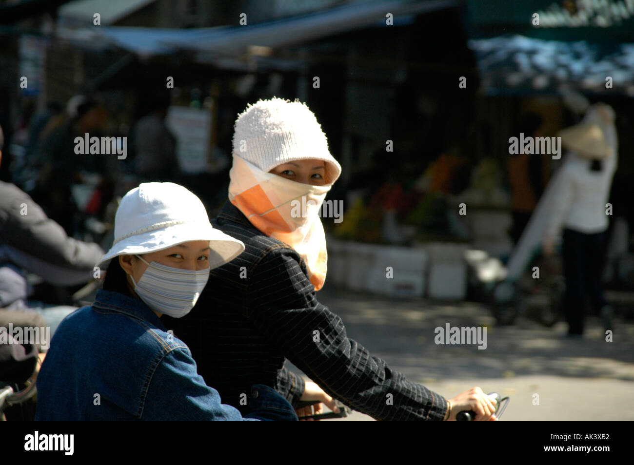 Zwei junge Frauen auf Fahrrädern schützen vor der Sonne Hai Phong Vietnam Teir Gesichter mit Tuch Stockfoto