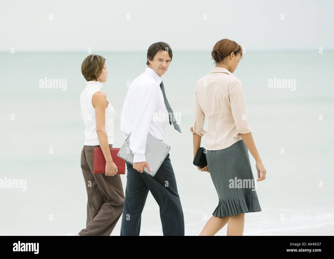 Business-Team zu Fuß am Strand, Geschäftsmann, über die Schulter in die Kamera schaut Stockfoto