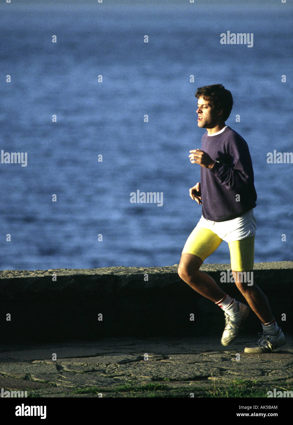 Ein Mann joggt entlang einer Ufermauer Stockfoto