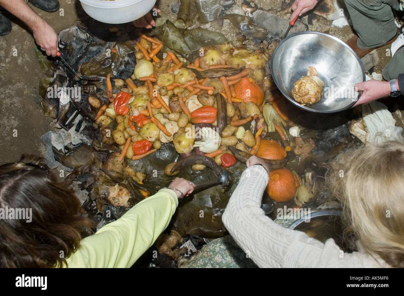 Eröffnung der Grube Ofen bei einem Curanto heißen Kochen in einer Grube Ofen Gemüse und Fleisch kochen auf Steinen Stockfoto