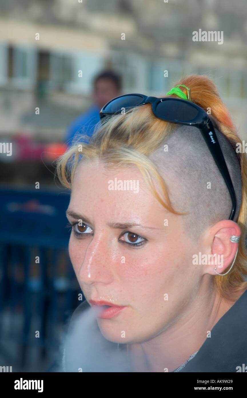 Ein Teenager im Alter von Mädchen mit einem Punk-Frisur Ausblasen Rauch einer Zigarette Stockfoto