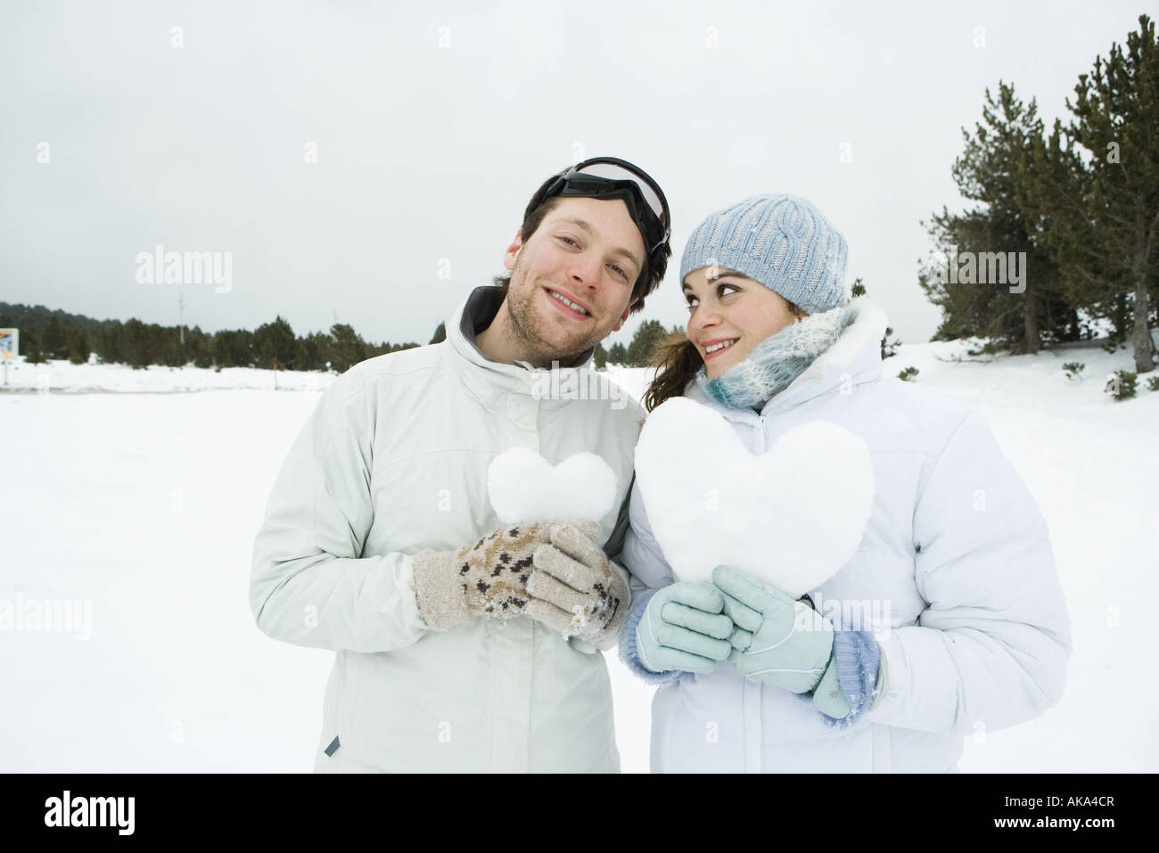 Junges Paar stehend nebeneinander halten Herz aus Schnee, Porträt Stockfoto