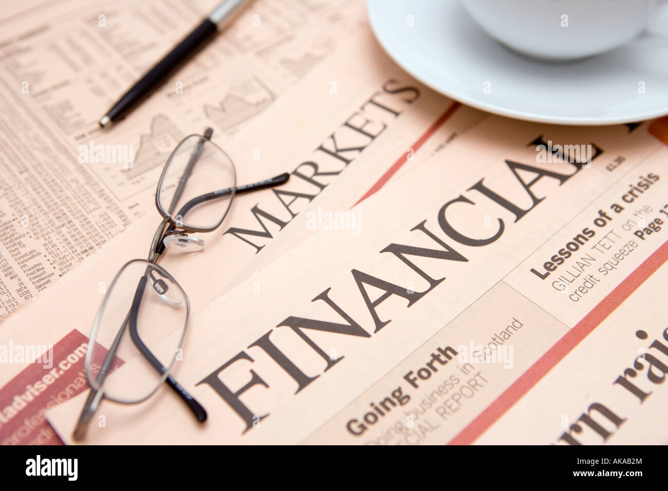 Finanzzeitung Studium Aktien und Aktien und Finanzmärkte für möglichen Gewinner mit einer Tasse Tee Stift und Brille Stockfoto