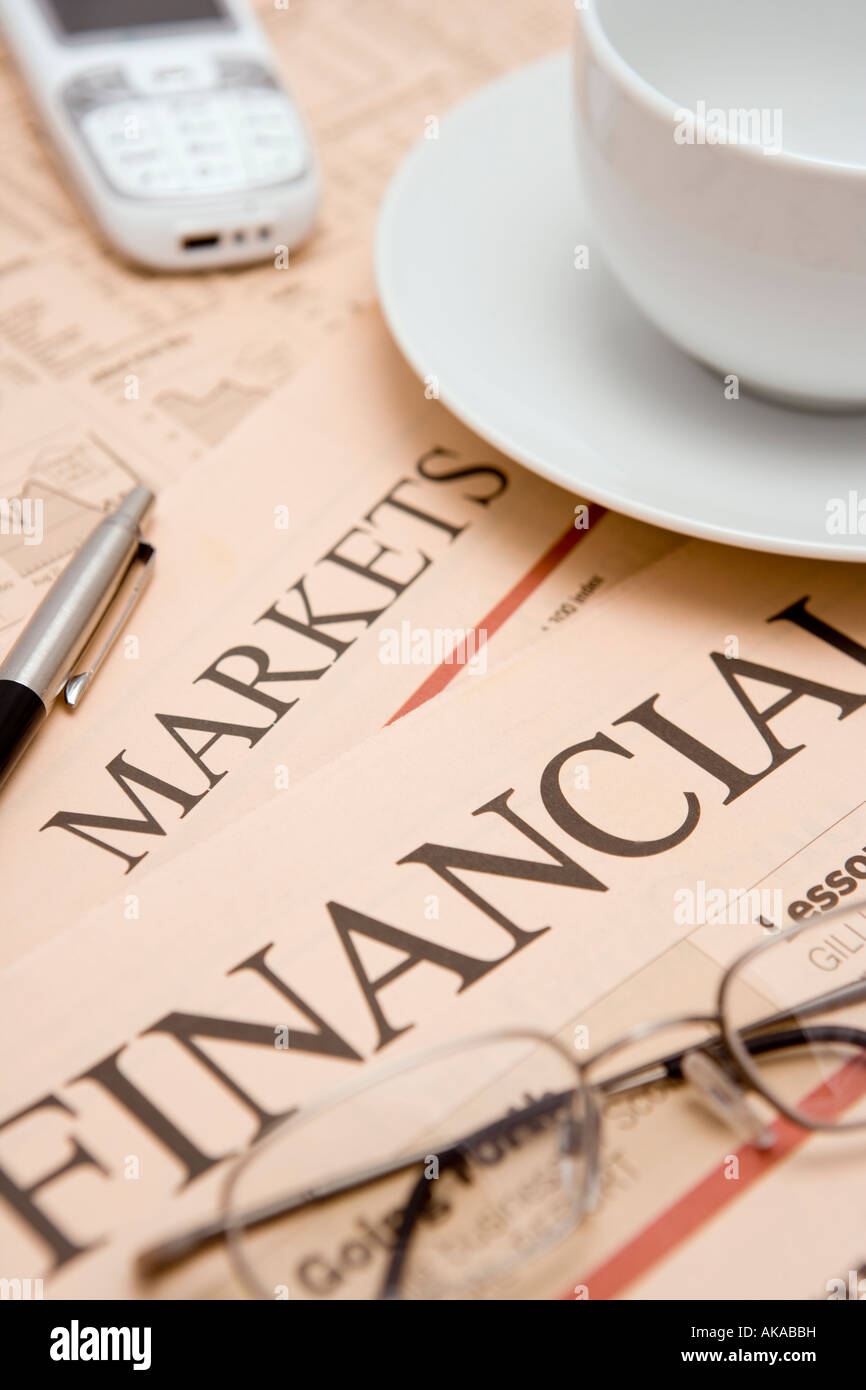 Wirtschaftsteil der Zeitung studieren die Finanznachrichten Aktien Aktien und Finanzmärkte mit Kaffee Gläser Stift Handy Stockfoto
