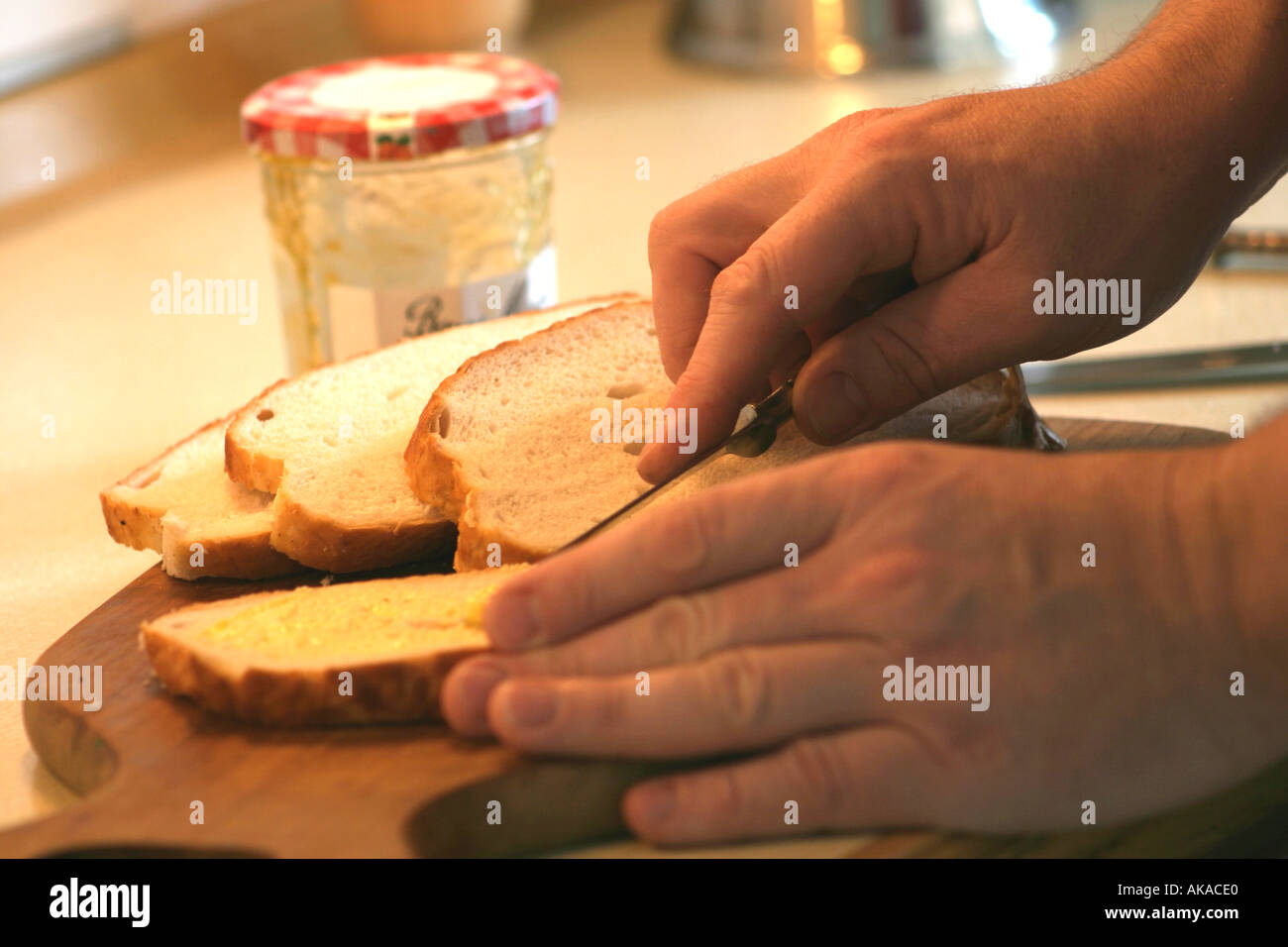 Nahaufnahme des Mannes geschnittenes Brot schmieren Stockfoto