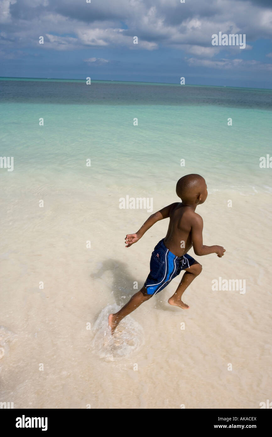 Ein kleiner Junge, läuft 4 Jahre, freudig im seichten Wasser, in der Nähe von Lyford Cay, New Providence, Bahamas. Stockfoto