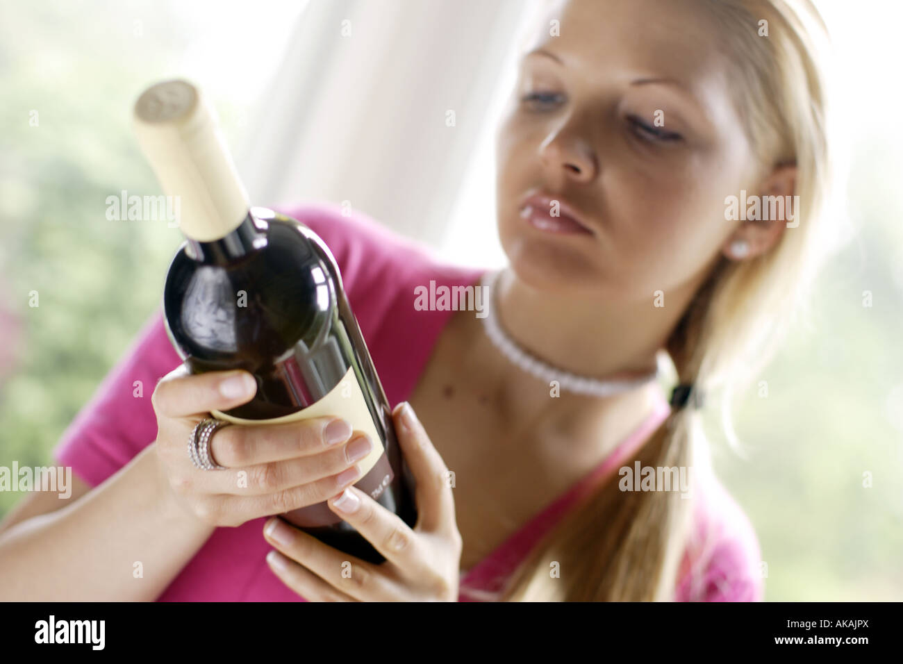 Frau betrachten Aufkleber auf Weinflasche Stockfoto