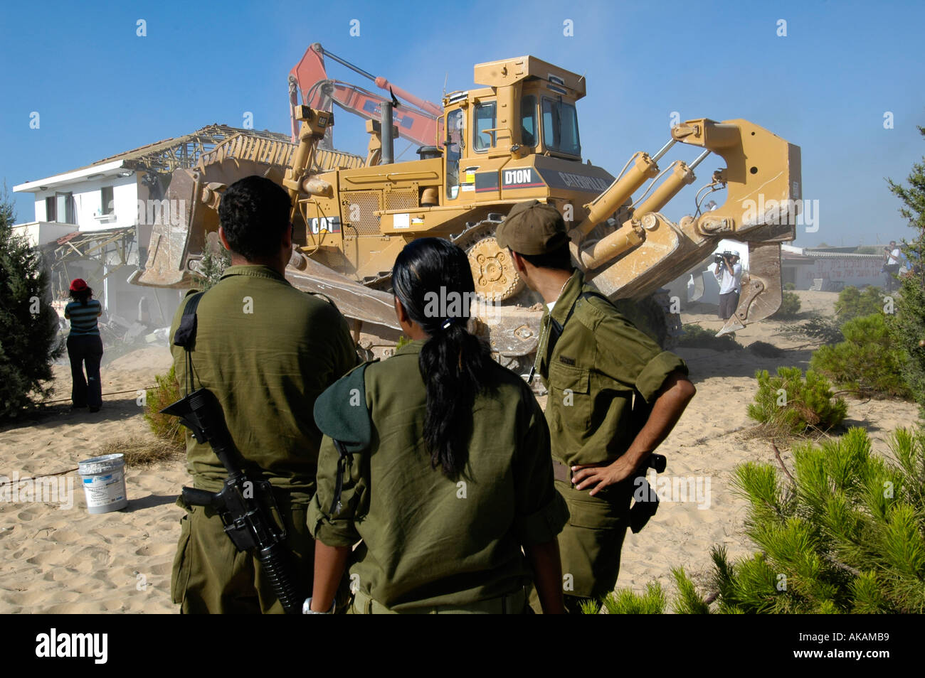 Israelische Soldaten sehen Sie eine Planierraupe demolieren verlassene Häuser jüdischer Siedler in der Abwicklung von Netzer hazani in Gaza Strip zu sein Stockfoto