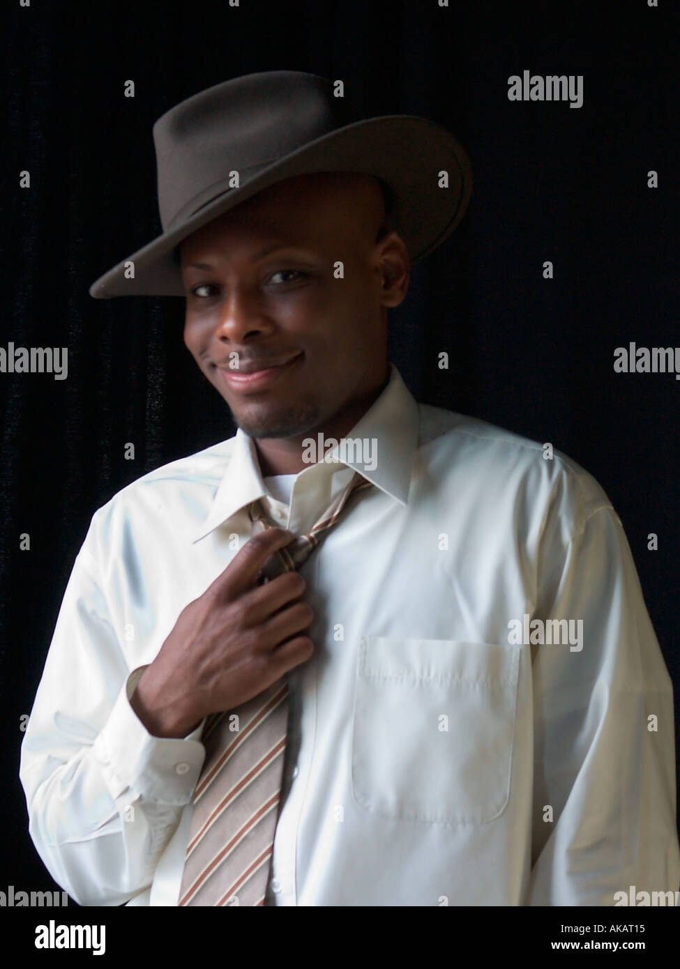Eine stilvolle schwarzer Rüde mit einem Fedora Anpassung seine Krawatte Stockfoto
