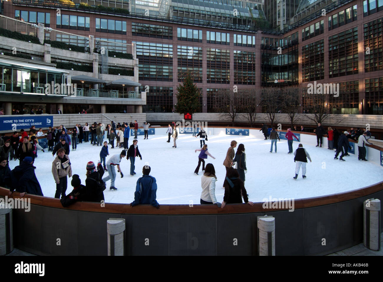 City of London sendet Menschen auf einer öffentlichen, im Winter geöffneten, kreisförmigen Eislaufbahn im Freien mit lustigen Schlittschuhläufern und Bürogebäuden außerhalb Englands Stockfoto