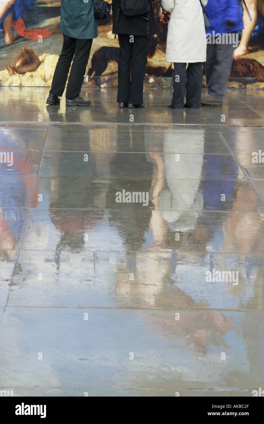 Menschen spiegelt sich in Regen durchnässt Pflaster Stockfoto