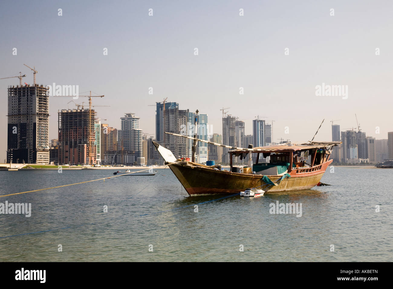 Wohngebäude Immobilieneinheiten in Al Sharjah; arabische Dhow traditionelle hölzerne Segelschiffe, die im arabischen Bach, Vereinigte Arabische Emirate, festgemacht sind Stockfoto