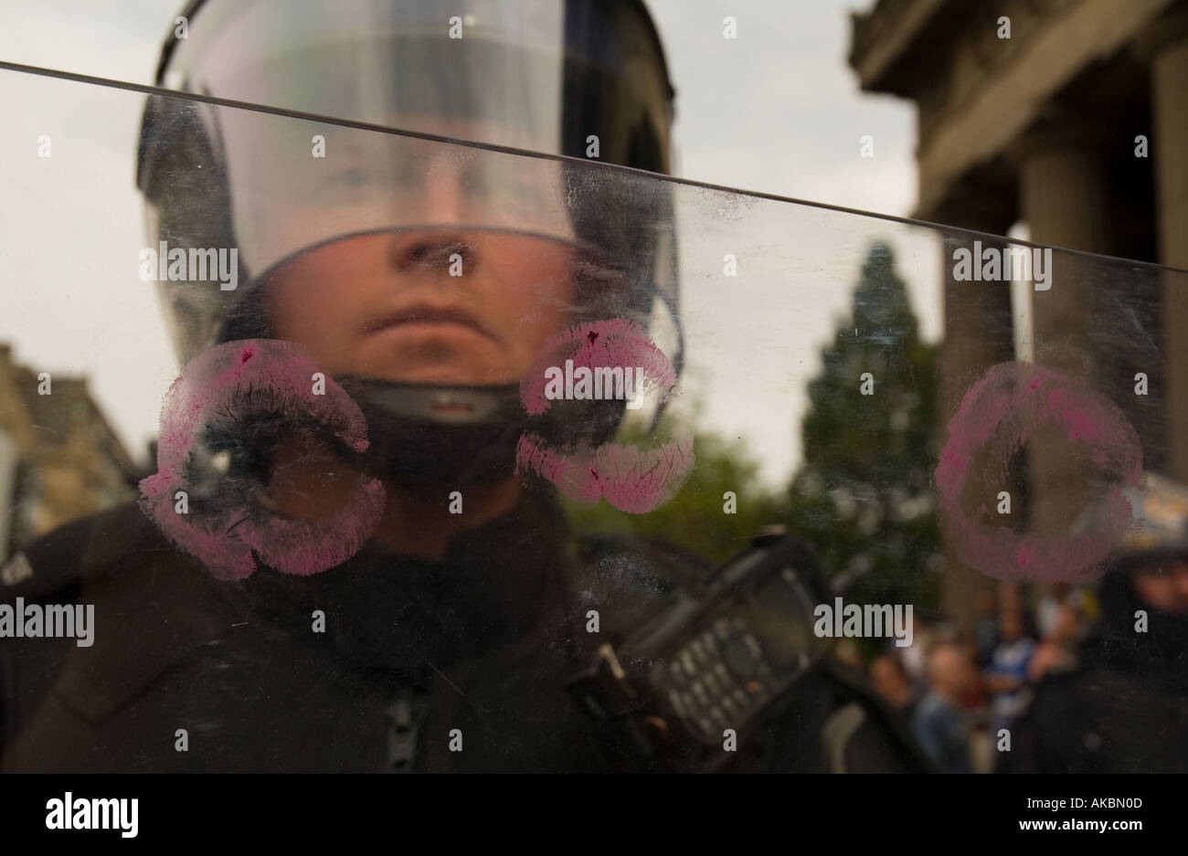 Riot-Polizist hinter seinem Schild bedeckt in heißen rosa Lippenstift küssen Stockfoto