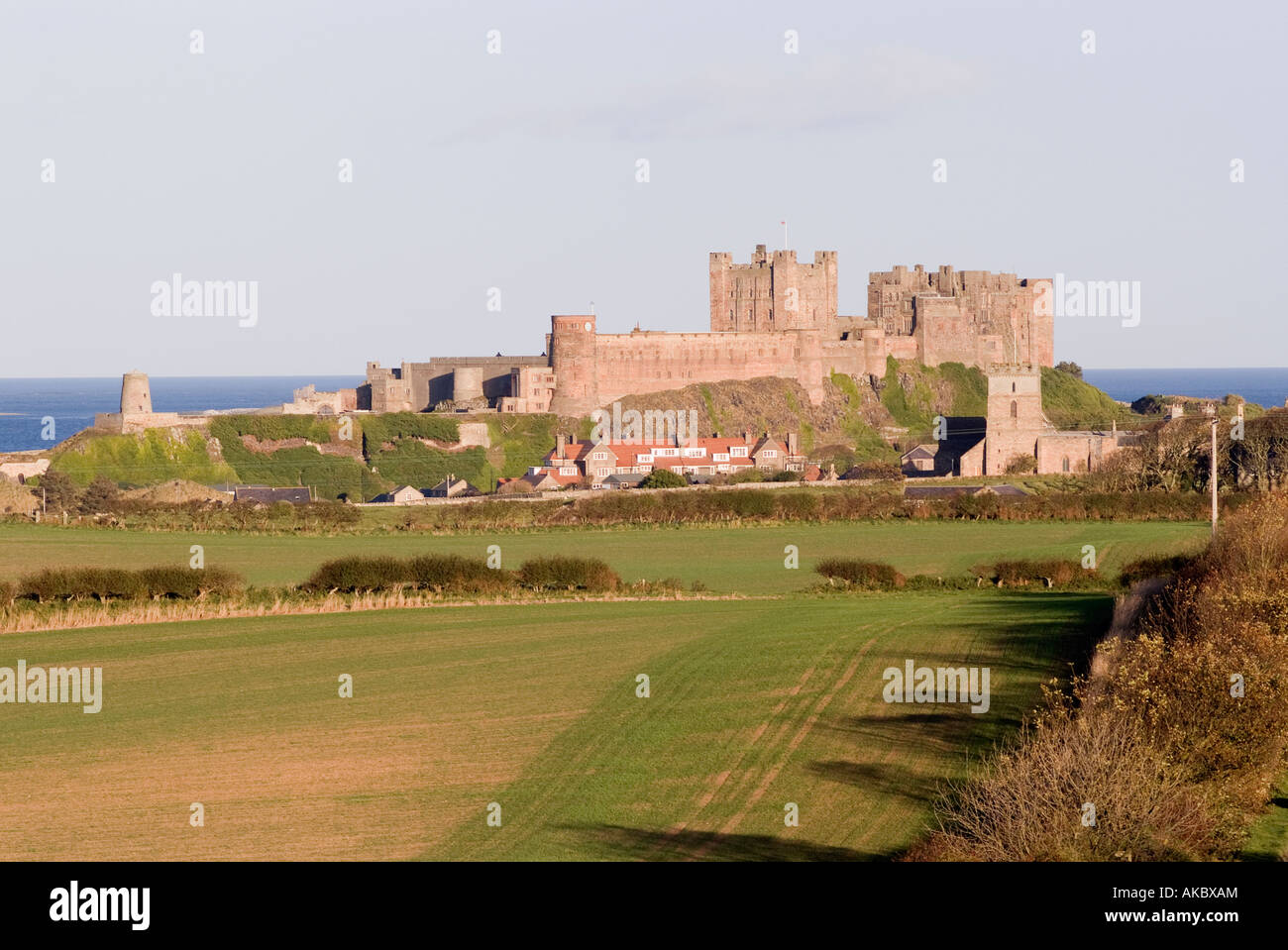 Blick auf Bamburgh Castle und Dorf gebadet im Sonnenschein Northumberland England United Kingdom Stockfoto