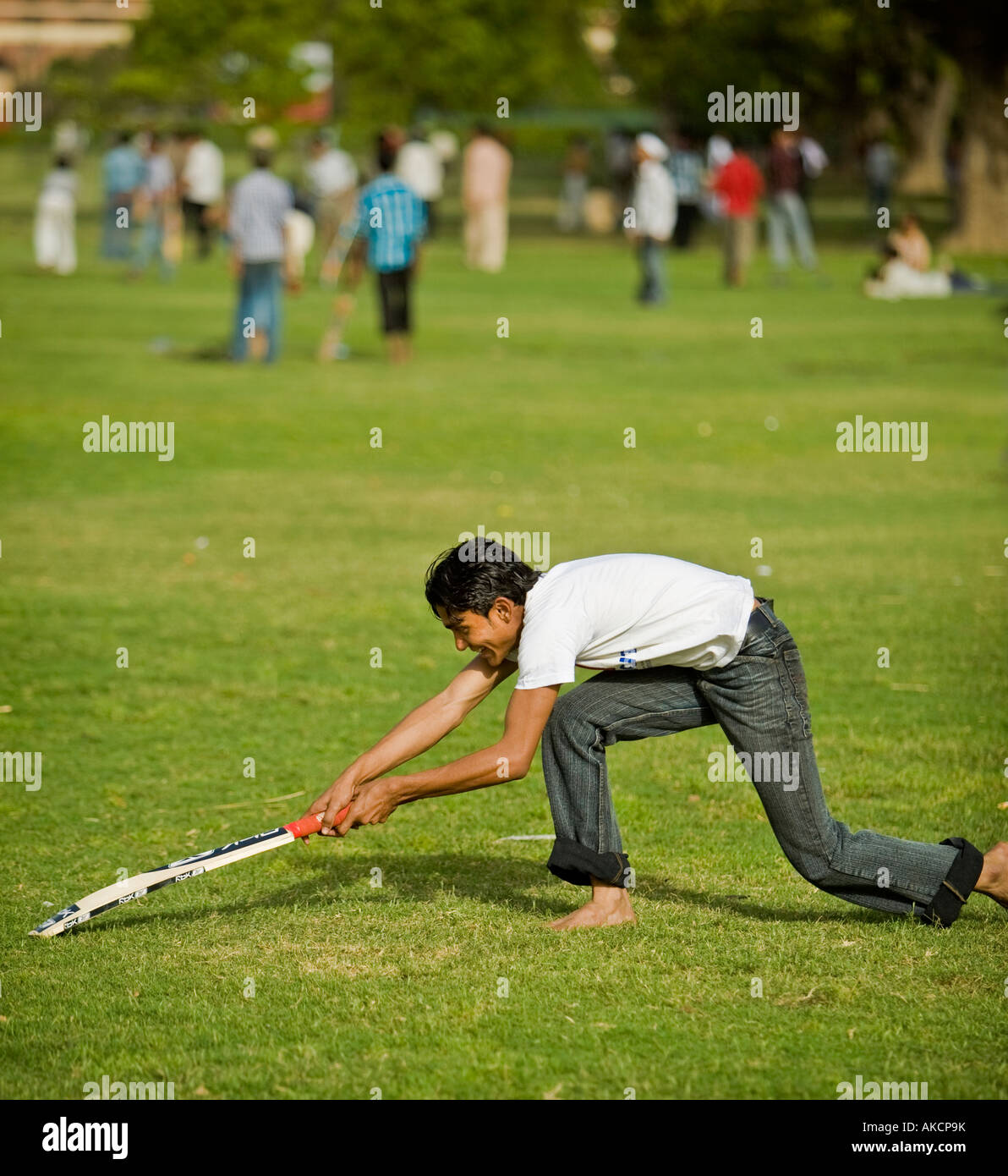 Ein junger Inder erstreckt sich um wieder an der Falte beim Spielen Cricket am India Gate. Delhi, Indien. Stockfoto