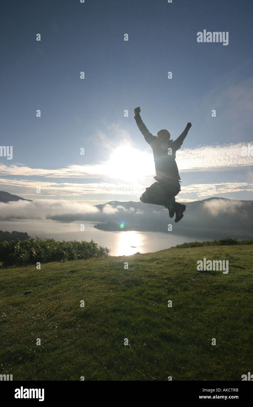 Ein stock Foto eines Mannes springen auf einem Berg bei Sonnenaufgang Stockfoto