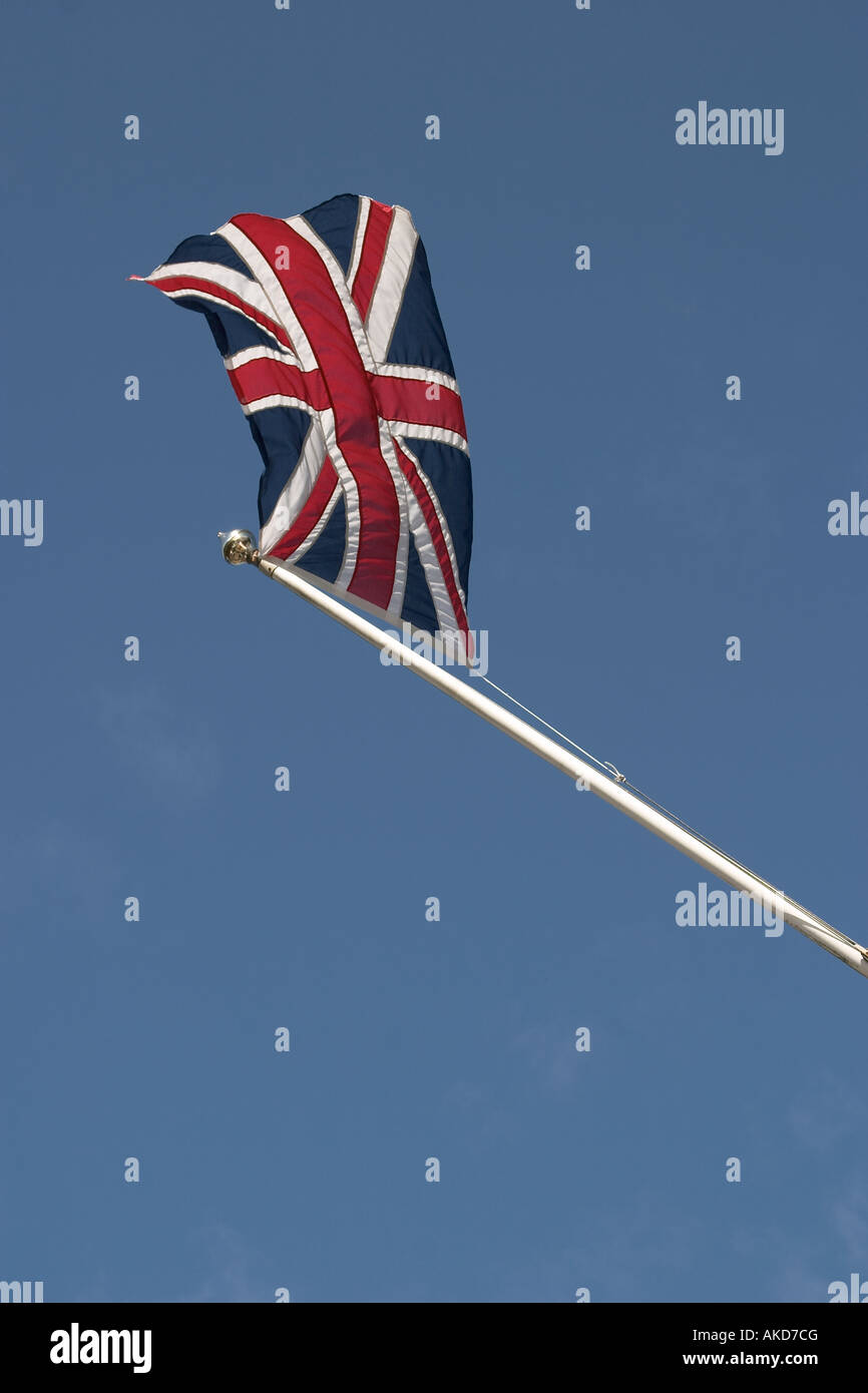 Union Jack am Fahnenmast gegen blauen Himmel zeigen Bewegung Stockfoto
