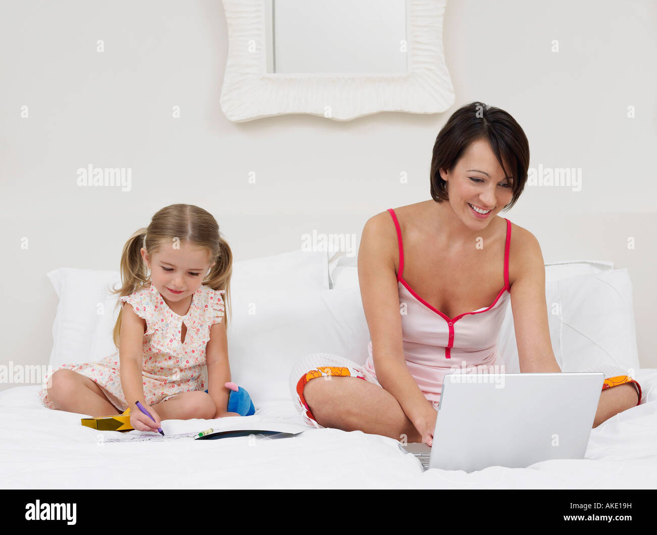 Mutter und Tochter Zeichnung und mit Laptop am Bett Stockfoto