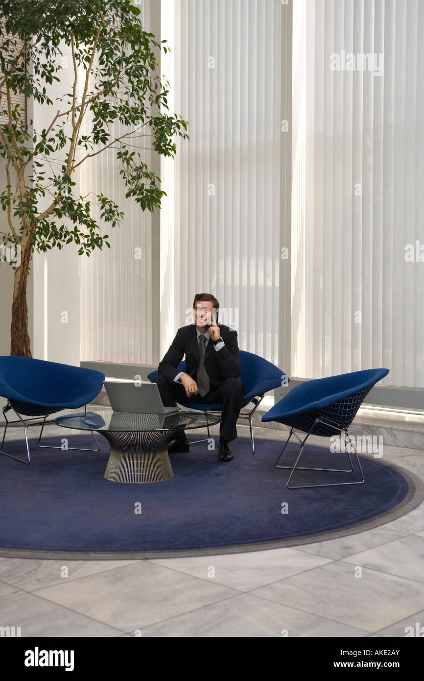 Business-Mann mit Handy mit Laptop im Büro lobby Stockfoto