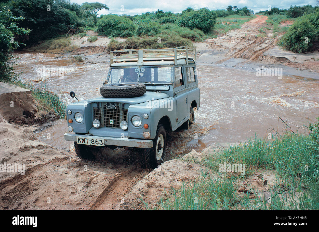 Graue kurze Radstand Landrover fording überfluteten Stream nach Starkregen in Tsavo East Nationalpark Kenia in Ostafrika Stockfoto