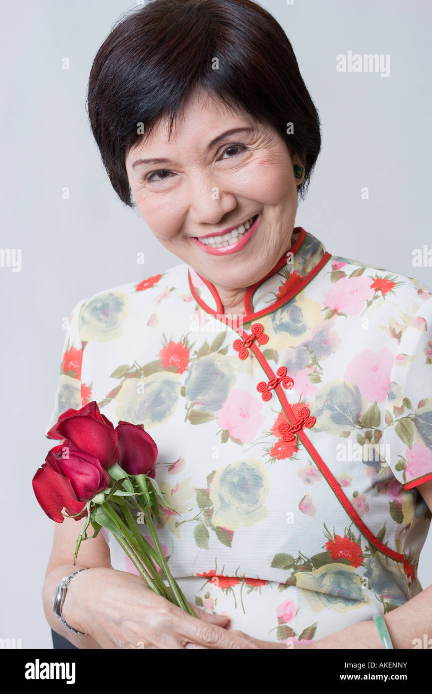 Porträt einer älteren Frau hält eine Reihe von Rose und lächelnd Stockfoto