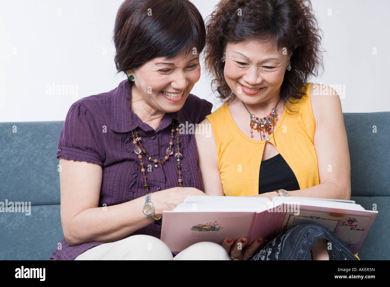 Nahaufnahme von zwei Frauen in Führungspositionen mit Blick auf ein Foto-Album und lächelnd Stockfoto