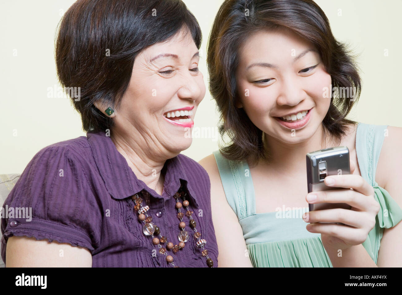 Nahaufnahme von einer älteren Frau und ihre Enkelin mit Blick auf ein Mobiltelefon und lächelnd Stockfoto
