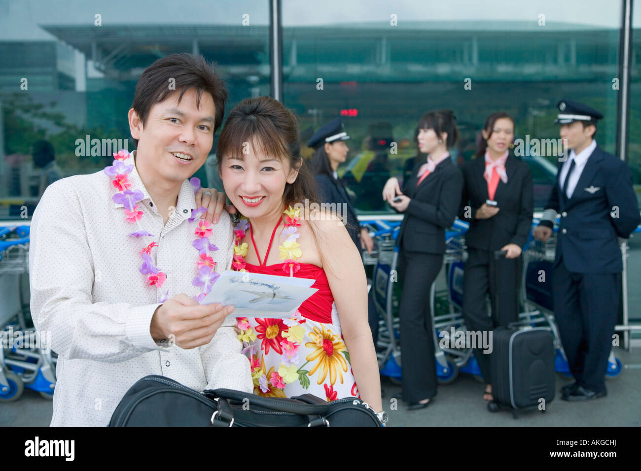 Älteres Paar ein Flugticket mit Piloten und Kabinenpersonal im Hintergrund stehend betrachten Stockfoto