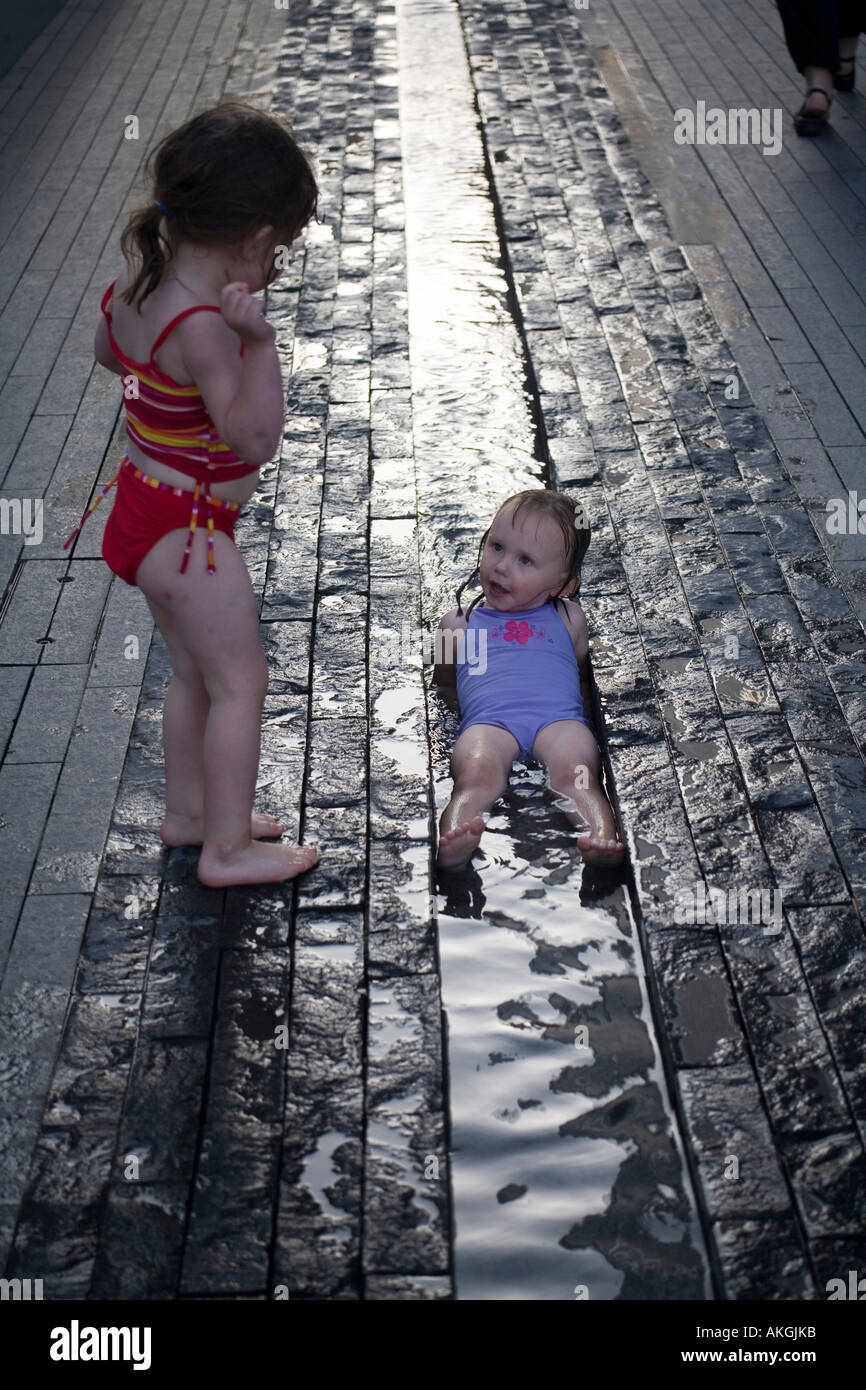 Baby-Mädchen spielen in Wasserabfluss an einem heißen Tag-London-UK Stockfoto