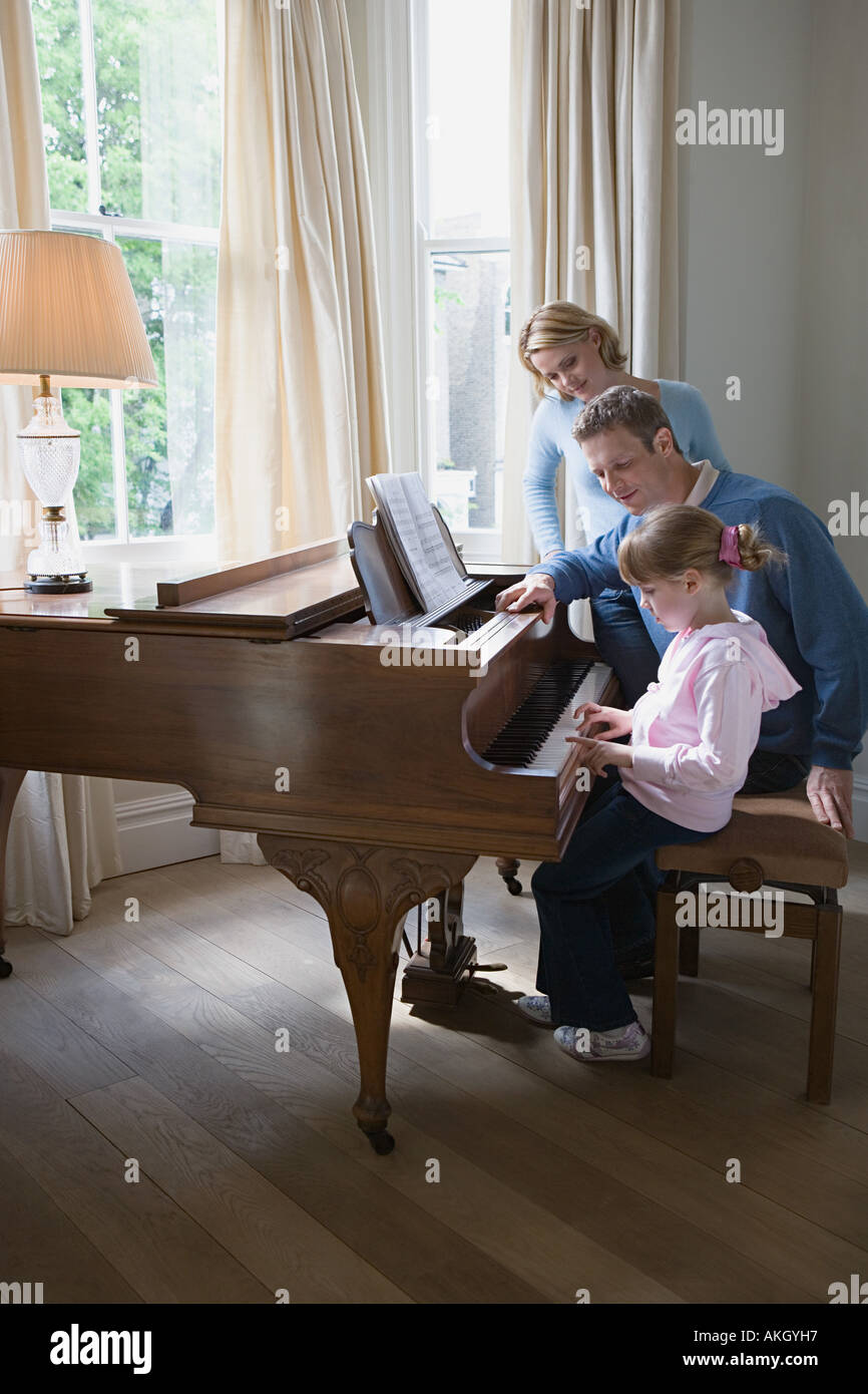 Eltern mit Tochter spielt Klavier Stockfoto