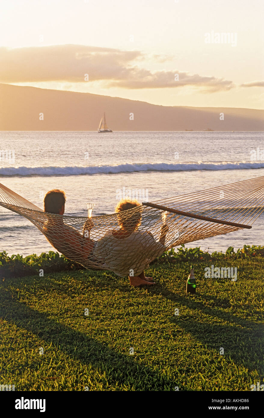 Paar sitzt in Hängematte Sonnenuntergang Flasche Champagner feiert das gute Leben auf der Insel Maui Stockfoto